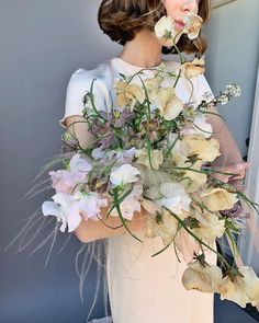 a woman in a white dress holding a bouquet of flowers and blowing a kiss on her lips