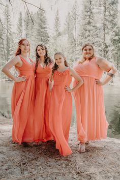 the bridesmaids are wearing coral colored dresses and posing for a photo in front of a lake