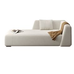 a white couch sitting on top of a white floor next to a book case and pillow