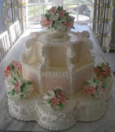 a large white cake sitting on top of a table covered in frosting and flowers