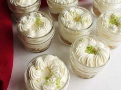 there are many desserts in small glass jars on the table with red and white cloth