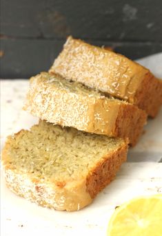 three slices of lemon bread sitting on top of a white cutting board next to a slice of lemon