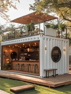 a small house made out of shipping containers with a bar on the roof and some stools