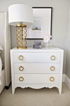 a white dresser with gold handles in a bedroom