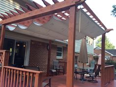 an outdoor patio with wooden decking and umbrellas on the pergolated area