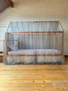 a bed that is sitting on top of a hard wood floor next to a brick wall