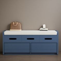 a blue dresser with two drawers and a purse on top, against a gray wall