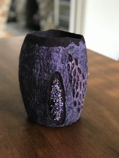 a purple vase sitting on top of a wooden table