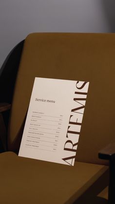 there is a menu on the back of a brown chair in front of a wall