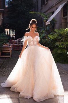 a woman in a wedding dress is walking down the street with her hand on her hip