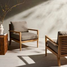 two wooden chairs sitting next to each other near a vase with flowers on top of it