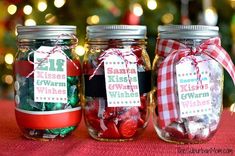 three jars filled with candy sitting on top of a table next to a christmas tree