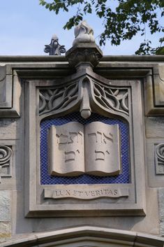 an old building with a book on the front and two birds sitting on top of it