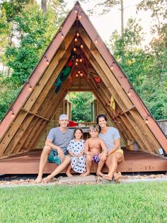 three people sitting in front of a wooden structure