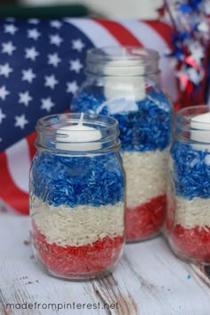 three jars filled with red, white and blue rice sitting next to an american flag