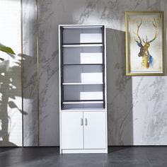 a tall white cabinet sitting in front of a painting on the wall next to a potted plant