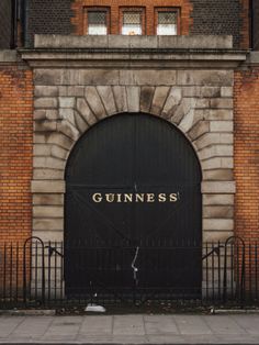 an old building with a black gate and the word guinness on it's door