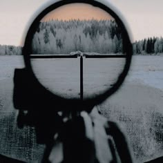 a person holding a magnifying glass looking at a field with trees in the background