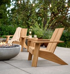 two wooden chairs sitting next to a fire pit