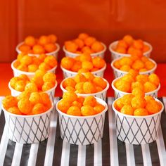 small white bowls filled with orange candies on a black and white striped tablecloth