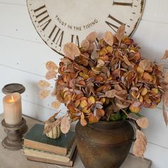 a vase filled with lots of flowers sitting on top of a table next to a clock