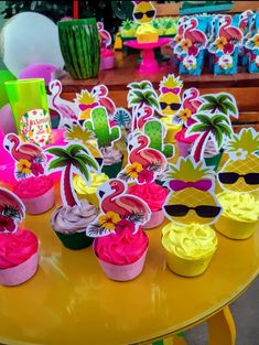 cupcakes decorated with pineapple, flamingos and sunglasses are on a table