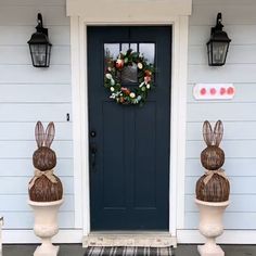 two easter decorations are on the front steps of a house with a blue door and wreath