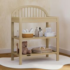 a teddy bear sitting on top of a wooden shelf next to a white towel rack