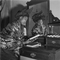 two women in traditional chinese clothing look at an open book