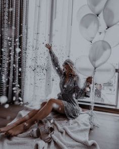 a woman is sitting on the floor with balloons and streamers in front of her