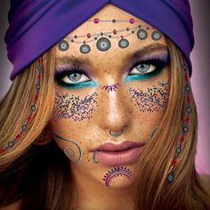 a woman with blue eyes and face paint is wearing a purple turban over her head