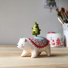 a small white polar bear with a christmas tree on it's back sitting on a table