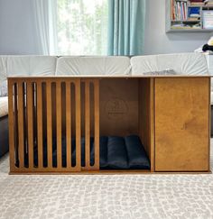 a living room with a white couch and a wooden cabinet in the middle that has blue pillows on it