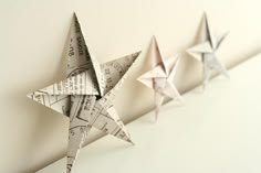 three origami stars are lined up on the wall, each with different directions