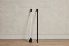 two black poles on the floor in front of a white wall