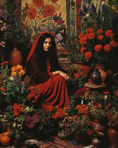 a woman sitting on the ground surrounded by flowers