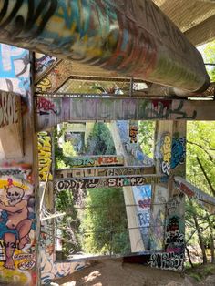 the underside of a bridge covered in grafitti and spray painted graffiti, with an overhang above it