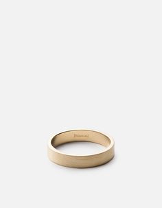 a gold wedding ring with a thin band on a plain surface, in front of a white background