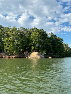 the water is calm and green as people stand on an island