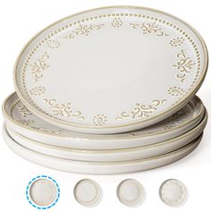 four white dinner plates with ornate designs on the rims, and three smaller ones