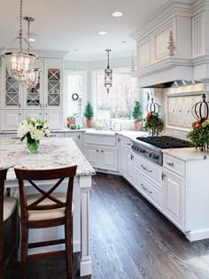 a large kitchen with white cabinets and marble counter tops, an island in the middle