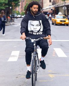 a man with dreadlocks is riding a bike in the middle of the street