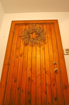 a wooden door with a tree decoration on the top and bottom panel, in front of a white wall