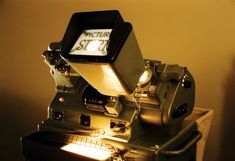 an old movie projector sitting on top of a table with its light turned on