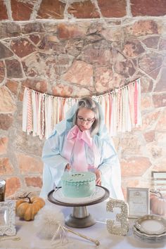 an older woman is cutting into a cake on a table with other items around her