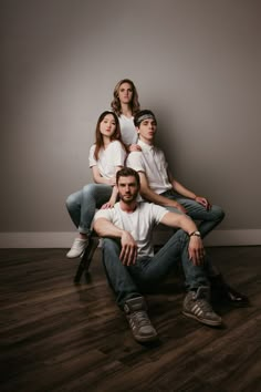 a group of people sitting on top of each other in front of a white wall