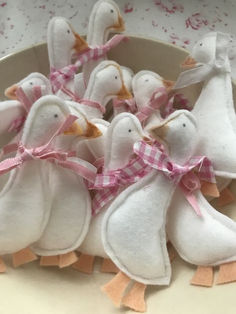 small white birds with pink bows in a bowl on a tablecloth covered plate, ready to be used as decorations