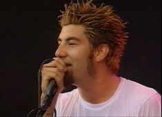 a man with dread locks on his head singing into a microphone