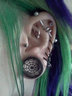 a person with green hair and piercings on their ears