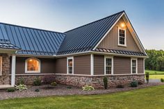 a house that has a metal roof and windows on the side of it, in front of a grassy field